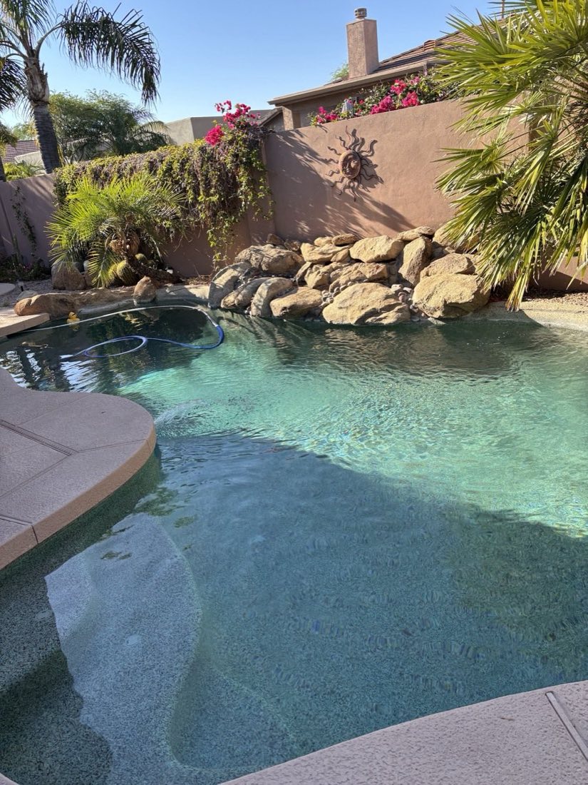 Crystal clear pebble pool with boulder waterfall maintained by Pristine Pool Service in Phoenix